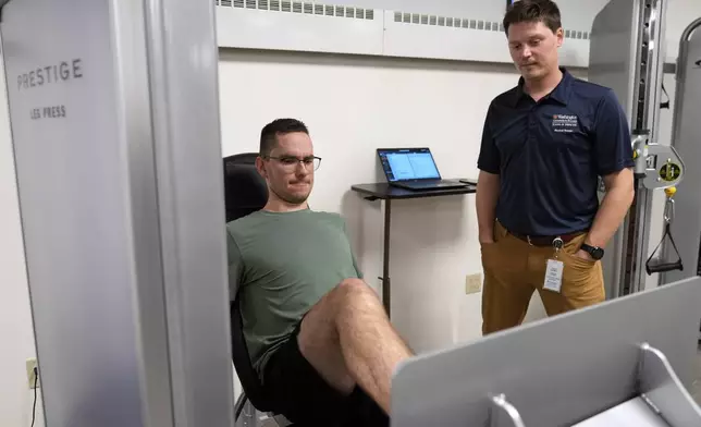 Physical therapist Tyler Detmer, right, watches as patient Jacob Bullard uses a leg press machine at WashU, Monday, Dec. 16, 2024, in St. Louis. (AP Photo/Jeff Roberson)