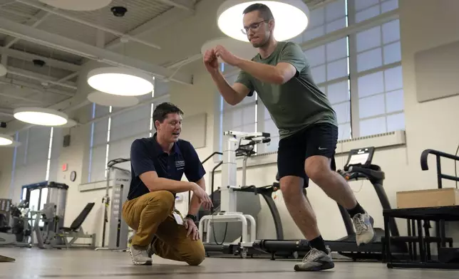 Physical therapist Tyler Detmer, left, works with patient Jacob Bullard at WashU, Monday, Dec. 16, 2024, in St. Louis. (AP Photo/Jeff Roberson)