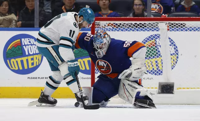 New York Islanders goaltender Marcus Hogberg (50) blocks San Jose Sharks center Luke Kunin (11) during the second period of an NHL hockey game, Saturday, Jan. 18, 2025, in Elmont, N.Y. (AP Photo/Corey Sipkin).