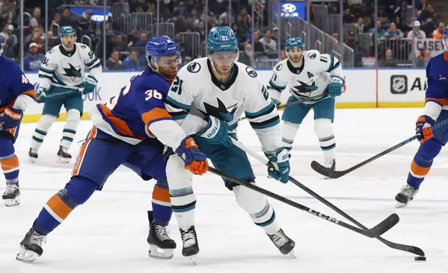 New York Islanders defenseman Isaiah George (36) defends San Jose Sharks center Alexander Wennberg (21) during the first period of an NHL hockey game, Saturday, Jan. 18, 2025, in Elmont, N.Y. (AP Photo/Corey Sipkin).