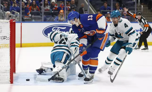New York Islanders center Mathew Barzal (13) scores against San Jose Sharks goaltender Alexandar Georgiev, left, as Sharks defenseman Cody Ceci (4) reacts during the second period of an NHL hockey game, Saturday, Jan. 18, 2025, in Elmont, N.Y. (AP Photo/Corey Sipkin).