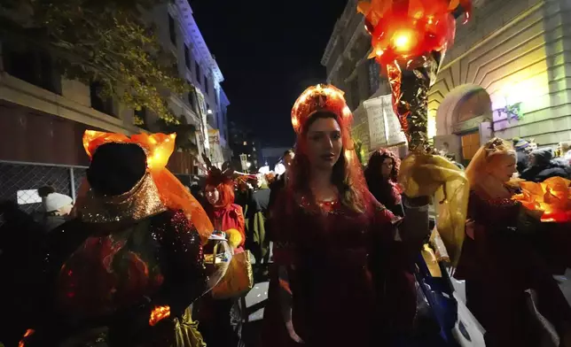 A woman holds a torch during the annual Krewe de Jeanne d'Arc parade, kicking off the Mardi Gras season, in New Orleans, Monday, Jan. 6, 2025. (AP Photo/Gerald Herbert)