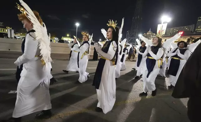 Parade-goers dressed as angels walk during the annual Krewe de Jeanne d'Arc parade, kicking off the Mardi Gras season, in New Orleans, Monday, Jan. 6, 2025. (AP Photo/Gerald Herbert)