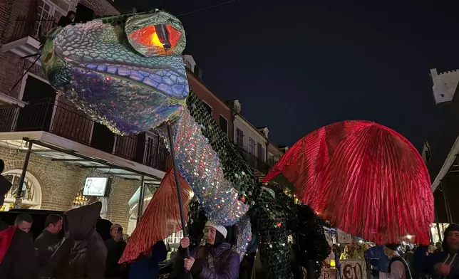 Volunteers carry a makeshift dragon through the streets of New Orleans famed French Quarter for the Joan of Arc parade kicking off the start of the city's carnival season Monday, Jan. 6, 2025. (AP Photo/Jack Brook)