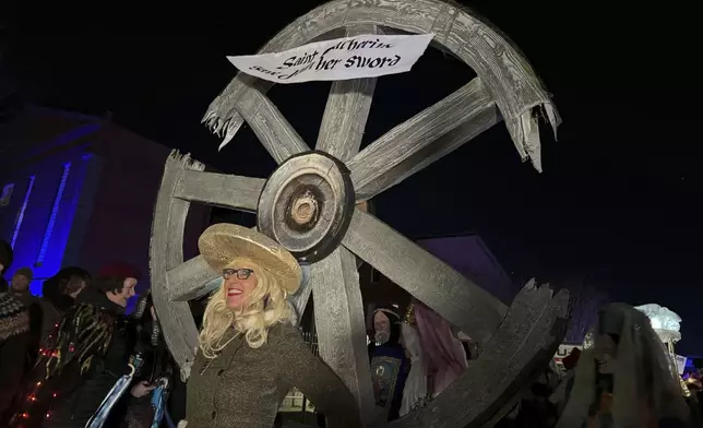 A marcher in the Joan of Arc parade carries a wheel symbolizing the sainthood of St. Catherine at the Joan of Arc parade on Monday, Jan. 6, 2025, in New Orleans. (AP Photo/Jack Brook)