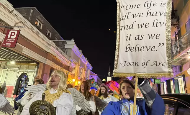 Marchers in the Joan of Arc parade on Monday, Jan. 6, 2025, in New Orleans, hold aloft a banner with a quote from the French saint. (AP Photo/Jack Brook)