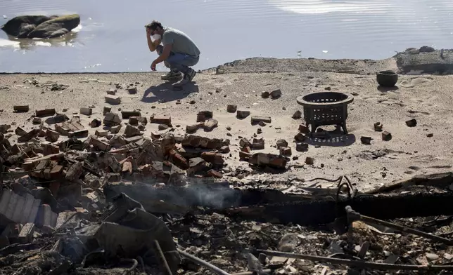 Luke Dexter kneels in front of his father's fire-ravaged beach front property in the aftermath of the Palisades Fire Friday, Jan. 10, 2025 in Malibu, Calif. (AP Photo/John Locher)