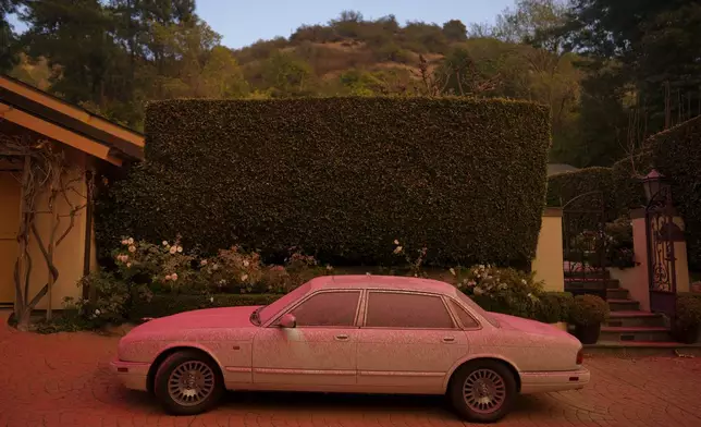 A vehicle is covered in retardant while crews battle the Palisades Fire in Mandeville Canyon Saturday, Jan. 11, 2025, in Los Angeles. (AP Photo/Eric Thayer)