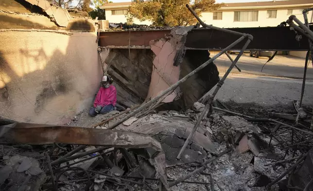 Kaegan Baron takes a moment as she sifts through the rubble of her mother's home after it was destroyed by the Palisades Fire in the Pacific Palisades neighborhood of Los Angeles, Saturday, Jan. 11, 2025. (AP Photo/John Locher)