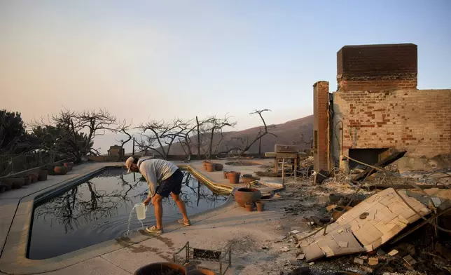 Garrett Yost gathers water from a pool while surveying his neighbors' fire-ravaged properties in the aftermath of the Palisades Fire in the Pacific Palisades neighborhood of Los Angeles, Friday, Jan. 10, 2025. (AP Photo/John Locher)