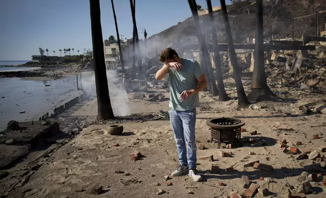 Luke Dexter reacts as he sifts through the remains of his father's fire-ravaged beach front property in the aftermath of the Palisades Fire Friday, Jan. 10, 2025 in Malibu, Calif. (AP Photo/John Locher)