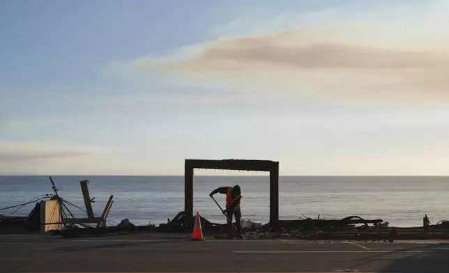 A worker clears debris from the Palisades Fire on Friday, Jan. 10, 2025, in Malibu, Calif. (AP Photo/Eric Thayer)