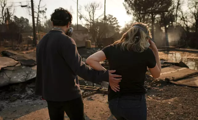 Homeowners Sohrab Nafici, left, and Christine Meinders return to their fire-ravaged neighborhood in the aftermath of the Eaton Fire Friday, Jan. 10, 2025 in Altadena, Calif. (AP Photo/Jae C. Hong)
