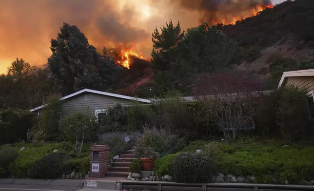 The Palisades Fire burns above a home in Mandeville Canyon, Saturday, Jan. 11, 2025, in Los Angeles. (AP Photo/Eric Thayer)
