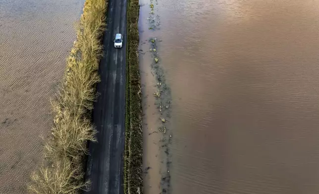 A car passes between flooded fields near the River Tone in Somerset, England, Monday, Jan. 6, 2025. (Ben Birchall/PA via AP)