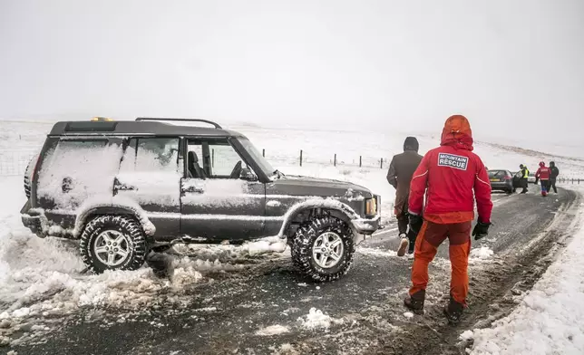 Members of a Mountain Rescue team help to clear cars from a snow drift near Ribblehead, in North Yorkshire, England, as large parts of the UK are facing heavy snow and freezing rain, which is likely to cause disruption, after two amber weather warnings came into force, on Monday Jan. 6, 2025. (Danny Lawson/PA via AP)