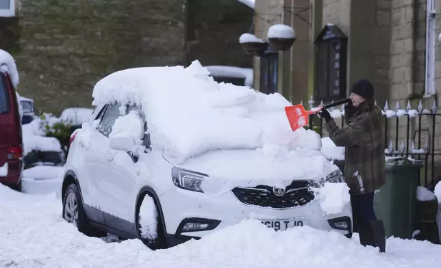 A person clears snow from a car in Allendale, England, Monday, Jan. 6, 2025. (Owen Humphreys/PA via AP)