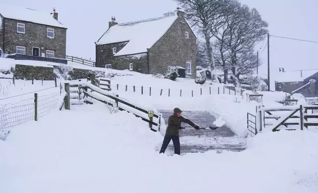 A person clears snow from a road near Allenheads, England, Monday, Jan. 6, 2025. (Owen Humphreys/PA via AP)