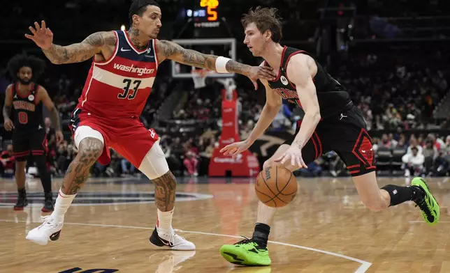 Chicago Bulls forward Matas Buzelis (14) dribbles to the hoop against Washington Wizards forward Kyle Kuzma (33) during the first half of an NBA basketball game, Wednesday, Jan. 1, 2025, in Washington. (AP Photo/Jess Rapfogel)