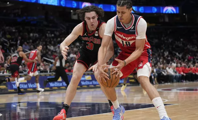 Chicago Bulls guard Josh Giddey (3) and Washington Wizards forward Kyshawn George (18) reach for the ball during the first half of an NBA basketball game, Wednesday, Jan. 1, 2025, in Washington. (AP Photo/Jess Rapfogel)