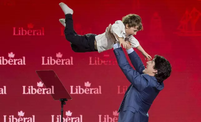 FILE - Prime Minister Justin Trudeau lifts his son Hadrien into the air following his speech at the federal Liberal national convention in Halifax on April 21, 2018. (Darren Calabrese/The Canadian Press via AP, File)