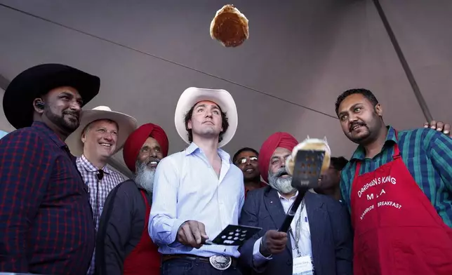 FILE - Liberal leader Justin Trudeau, center, flips pancakes at a Stampede breakfast in Calgary, Alta., on July 7, 2013. (Jeff McIntosh/The Canadian Press via AP, File)