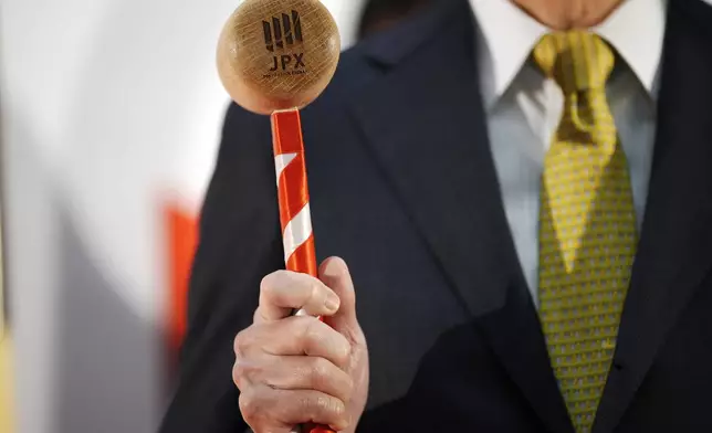 A guest prepares to pose with a wooden hummer to toll the bell prior to a ceremony marking the start of this year's trading Monday, Jan. 6, 2025, at the Tokyo Stock Exchange in Tokyo. (AP Photo/Eugene Hoshiko)