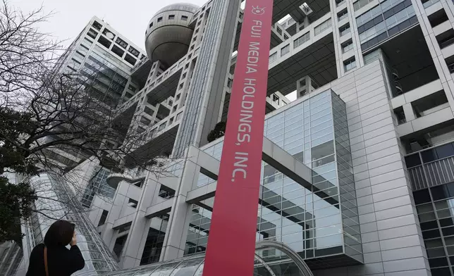 A person takes a photo of the FCG building, holding the Fuji Television and its parent company Fuji Media Holdings, in Tokyo, Monday, Jan. 27, 2025. (AP Photo/Eugene Hoshiko)