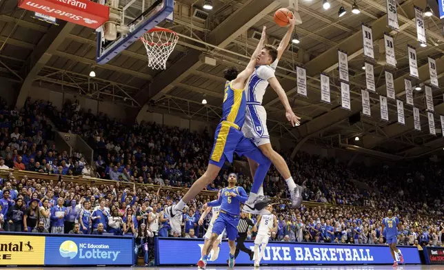 Duke's Cooper Flagg, right, dunks over Pittsburgh's Guillermo Diaz Graham (25) during the second half of an NCAA college basketball game in Durham, N.C., Tuesday, Jan. 7, 2025. (AP Photo/Ben McKeown)