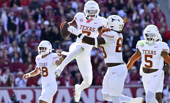FILE - Texas defensive back Jahdae Barron (7) celebrates with teammate Barryn Sorrell (88) after making in interception against Arkansas during the first half of an NCAA college football game Saturday, Nov. 16, 2024, in Fayetteville, Ark. (AP Photo/Michael Woods, File)