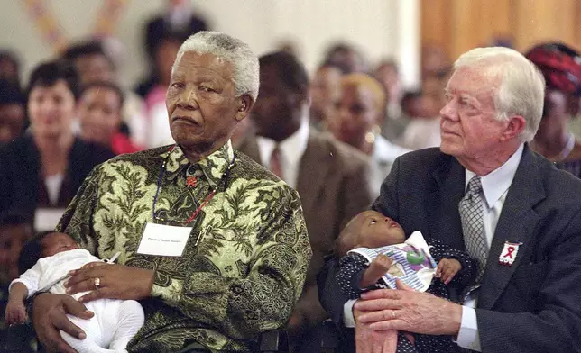 FILE - Former South African President Nelson Mandela, left, and former U.S. President Jimmy Carter, right, hold HIV-positive babies at the Zola Clinic in Soweto, March 7, 2002. (AP Photo/Nonthemba Kwela, File)