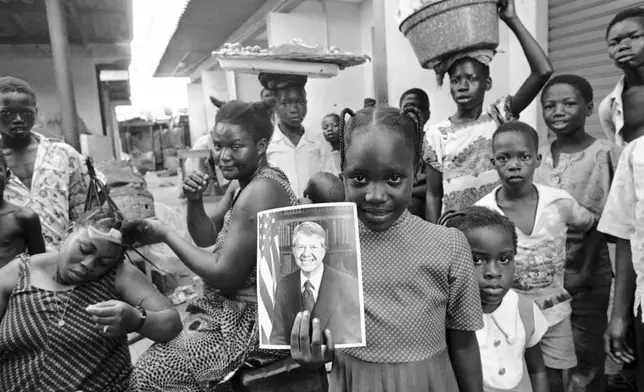 FILE - A girl holds a portrait of U.S. President Jimmy Carter in a market in Lagos, Nigeria, March 31, 1978, the day of his arrival for a state visit, the first to Africa by an American president. (AP Photo/Dieter Endlicher, File)