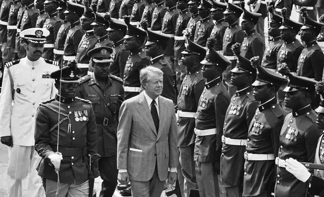 FILE - U.S. President Jimmy Carter reviews honor guards during arrival ceremonies at the Dodan Barracks in Lagos, Nigeria, April 1, 1978. (AP Photo, File)