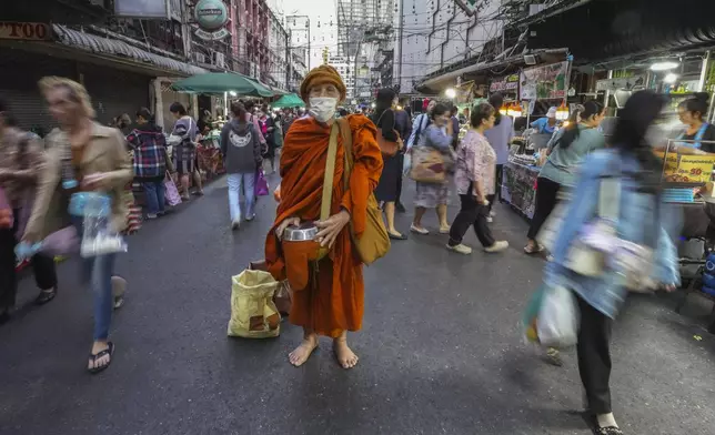 A Thai Buddhist monk wears winter hat as he waits for offerings in Bangkok, Thailand, Thursday, Jan. 16, 2025. (AP Photo/Sakchai Lalit)