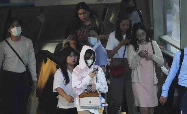 A woman, foreground, wears sweater in Bangkok, Thailand, Thursday, Jan. 16, 2025. (AP Photo/Sakchai Lalit)