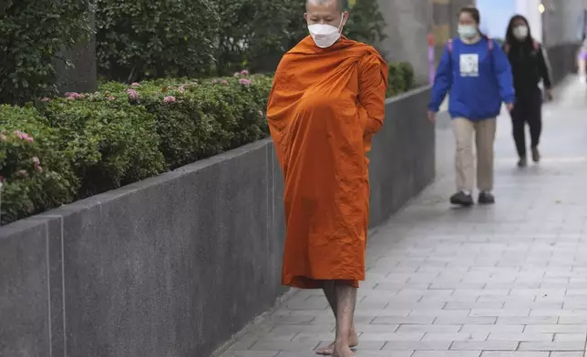 A Buddhist monk holds a bowl for morning alms in Bangkok, Thailand, Thursday, Jan. 16, 2025. (AP Photo/Sakchai Lalit)