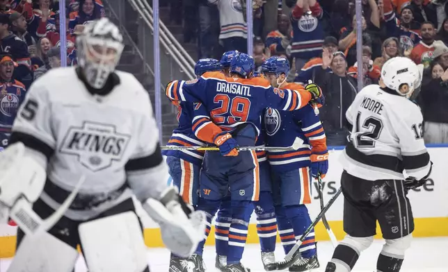 Los Angeles Kings goalie Darcy Kuemper, left, and Trevor Moore (12) look on as Edmonton Oilers celebrate after a goal during second-period NHL hockey game action in Edmonton, Alberta, Monday, Jan. 13, 2025. (Jason Franson/The Canadian Press via AP)