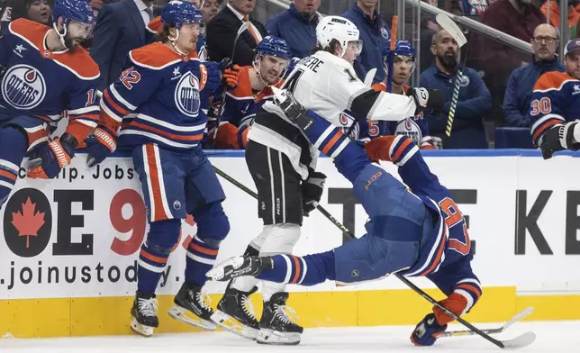 Los Angeles Kings' Alex Laferriere (14) slams Edmonton Oilers' Connor McDavid (97) during second-period NHL hockey game action in Edmonton, Alberta, Monday, Jan. 13, 2025. (Jason Franson/The Canadian Press via AP)