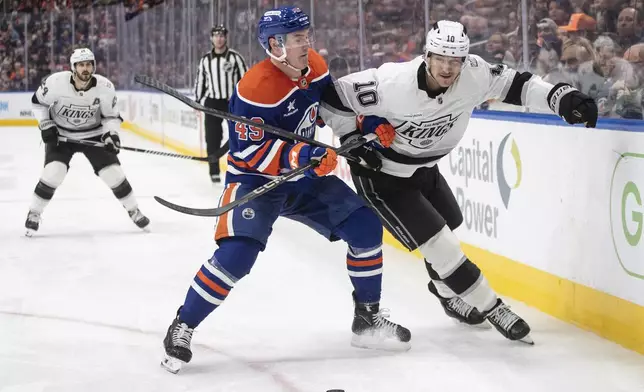 Los Angeles Kings' Tanner Jeannot (10) and Edmonton Oilers' Ty Emberson (49) battle for the puck during the third period of an NHL hockey game in Edmonton, Alberta, Monday, Jan. 13, 2025. (Jason Franson/The Canadian Press via AP)