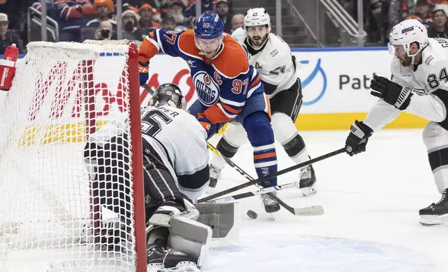Los Angeles Kings goalie Darcy Kuemper, front left, makes a save against Edmonton Oilers' Connor McDavid (97) during second-period NHL hockey game action in Edmonton, Alberta, Monday, Jan. 13, 2025. (Jason Franson/The Canadian Press via AP)