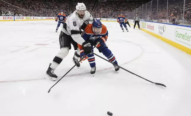 Los Angeles Kings' Joel Edmundson (6) and Edmonton Oilers' Zach Hyman (18) battle for the puck during second-period NHL hockey game action in Edmonton, Alberta, Monday, Jan. 13, 2025. (Jason Franson/The Canadian Press via AP)