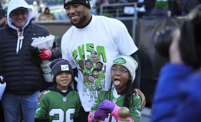 Philadelphia Eagles running back Saquon Barkley poses for photos with kids before an NFL football game against the New York Giants on Sunday, Jan. 5, 2025, in Philadelphia. (AP Photo/Chris Szagola)