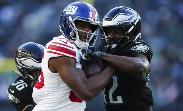 New York Giants tight end Chris Manhertz (85) is tackled by Philadelphia Eagles safety Tristin McCollum (36) and Philadelphia Eagles linebacker Oren Burks (42) during the second half of an NFL football game Sunday, Jan. 5, 2025, in Philadelphia. (AP Photo/Derik Hamilton)