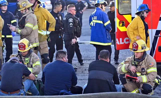 Firefighters tend to people after a plane crashed through the roof of a building near Fullerton airport on Thursday, Jan. 2, 2025, in Fullerton, Calif. (Jeff Gritchen, Orange County Register/The Orange County Register via AP)