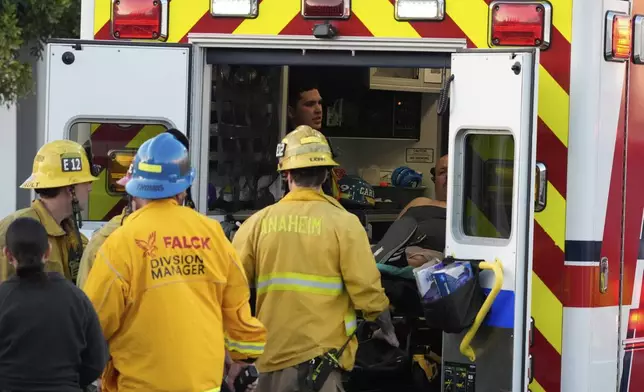 Firefighters load a person onto an ambulance after a small plane crashed into a commercial building on Thursday, Jan. 2, 2025, in Fullerton, Calif. (AP Photo/Damian Dovarganes)