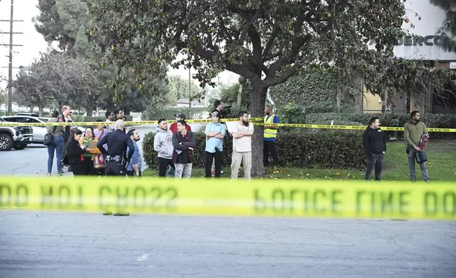 Workers stand near police lines at the scene of a small plane crash, Thursday, Jan. 2, 2025, in Fullerton, Calif. (AP Photo/Kyusung Gong)