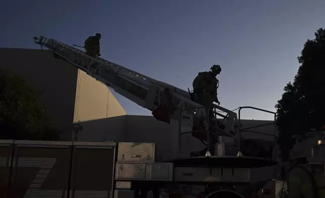 Firefighter walk down a ladder outside a building where a plane crash occurred Thursday, Jan. 2, 2025, in Fullerton, Calif. (AP Photo/Kyusung Gong)