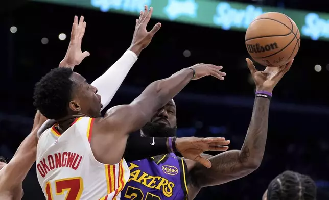 Los Angeles Lakers forward LeBron James, right, shoots as Atlanta Hawks forward Onyeka Okongwu defends during the first half of an NBA basketball game, Friday, Jan. 3, 2025, in Los Angeles. (AP Photo/Mark J. Terrill)