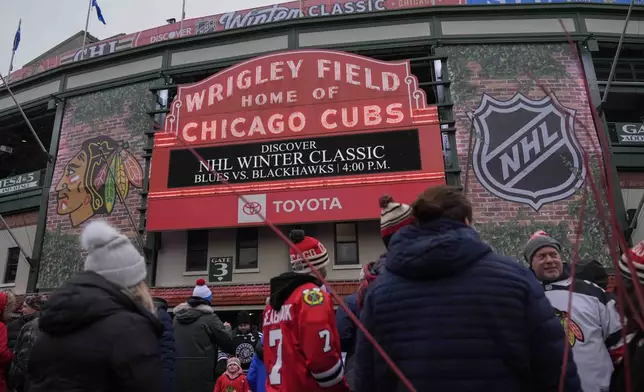 Fans hang outside of Wrigley Field before the NHL Winter Classic outdoor hockey game between the Chicago Blackhawks and St. Louis Blues, Tuesday, Dec. 31, 2024, in Chicago. (AP Photo/Erin Hooley)