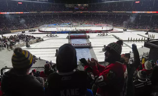 Fans celebrate after a goal by the Chicago Blackhawks against the St. Louis Blues during the third period of the NHL Winter Classic outdoor hockey game at Wrigley Field, Tuesday, Dec. 31, 2024, in Chicago. (AP Photo/Erin Hooley)